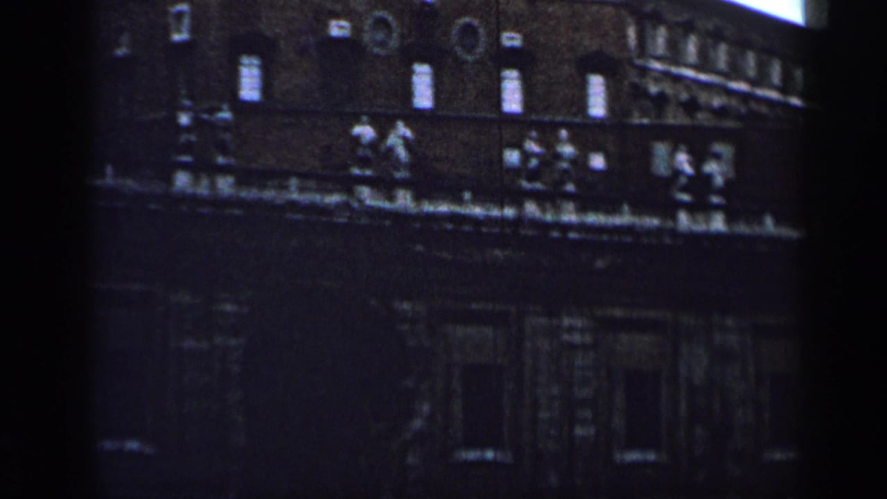 Dark masonry building facade with windows and roofline statues.