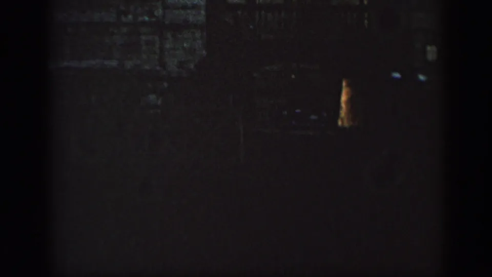 1962 Cuba frame showing a shadowed building wall, faint window shapes, and a small warm-toned light or reflection at right.