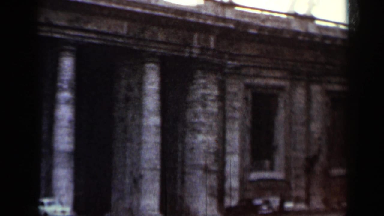 Stone building facade with columns and dark window openings, seen through heavy frame shadow.