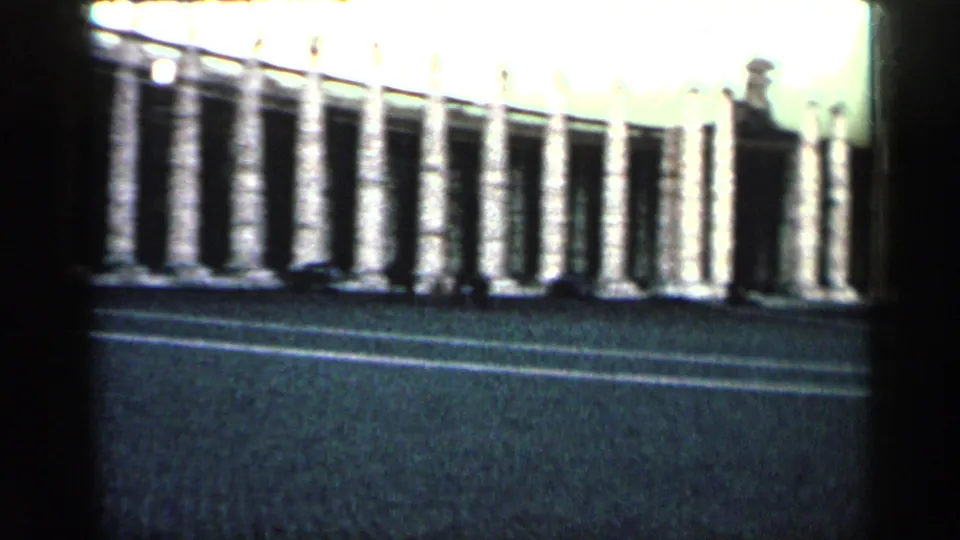 1962 Cuba 8mm view across a paved street toward a long heritage building with repeated stone columns.