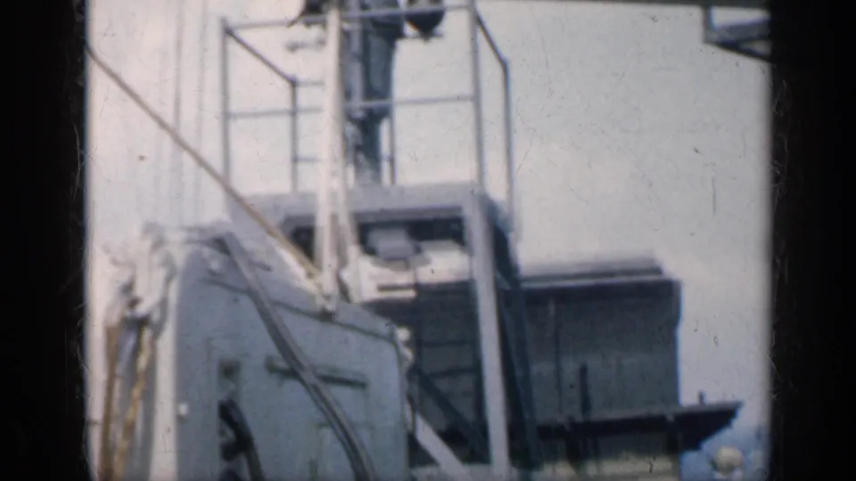 Low-angle view of carrier railings, stairs, and industrial deck structures in 1962 Cuba-context naval home-movie footage.