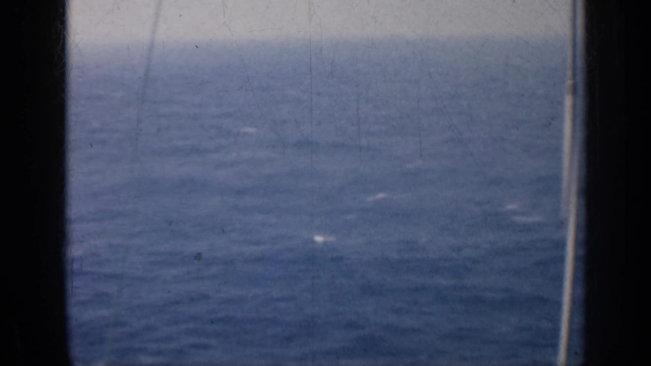 Blue ocean and hazy horizon seen through dark vertical framing.