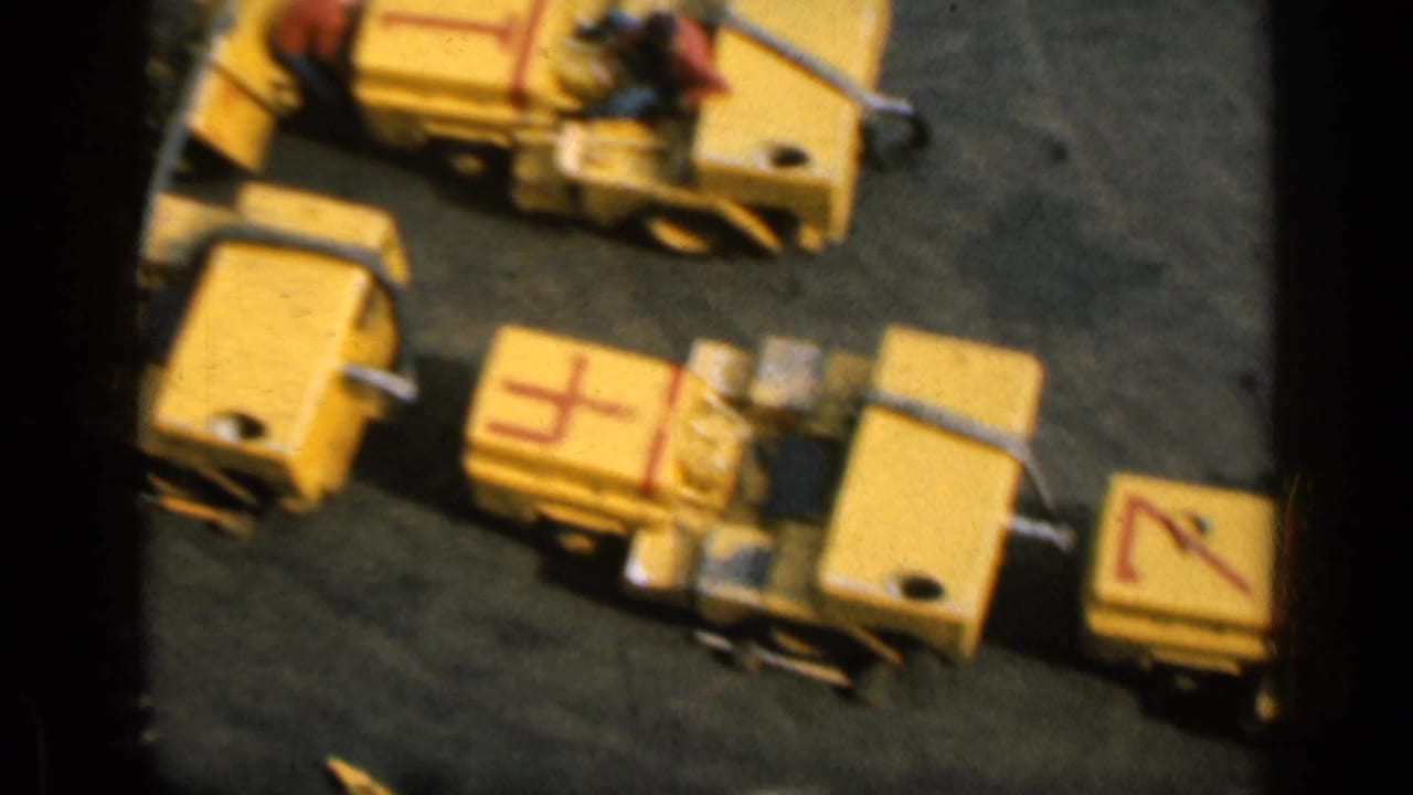 Yellow industrial machines on a dark ship deck with partial workers nearby.