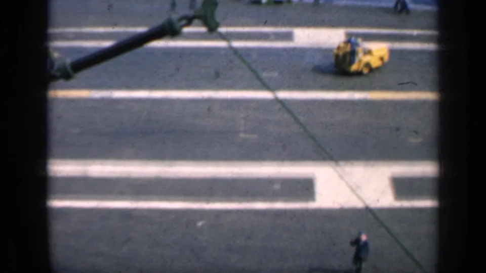 Wide ship-deck view with painted white lines, a small yellow machine, a cable, and distant workers in 1962 Cuba footage.