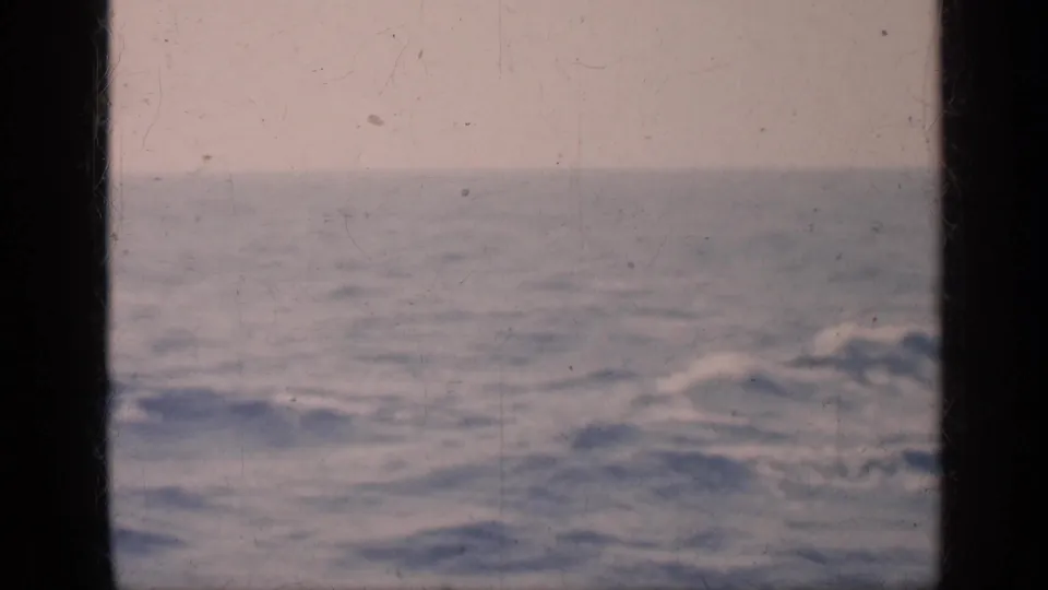 Faded 8mm frame of the sea near Cuba, with low waves, pale sky, and a dark center border from the film or view.