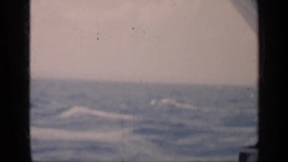 Soft 8mm frame from Cuba metadata showing open ocean, pale sky, dark border shapes, and faded film texture.