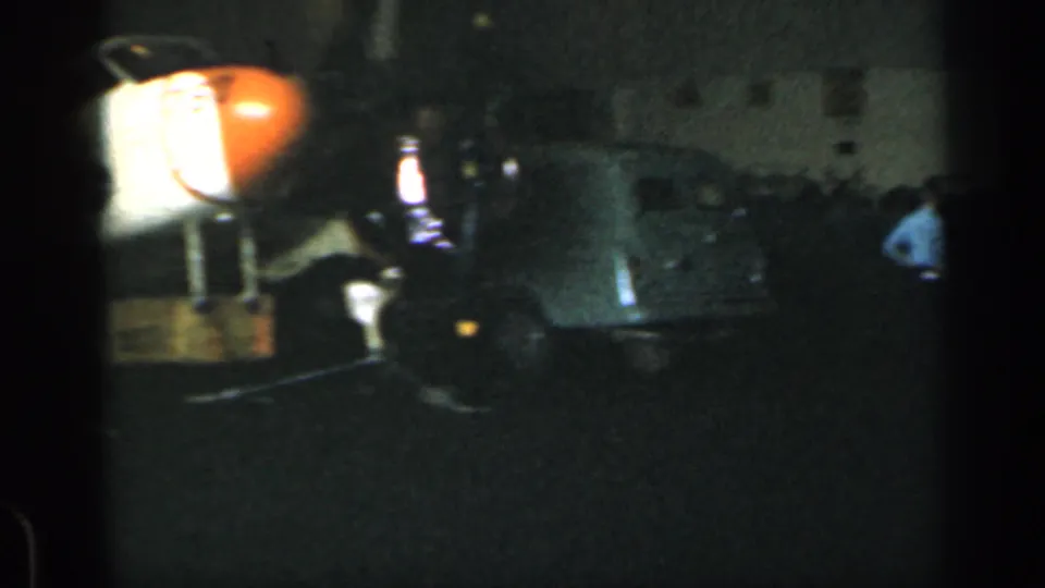 Nighttime 1962 Cuba footage shows a classic car with people nearby, captured in soft, underexposed home-movie light.