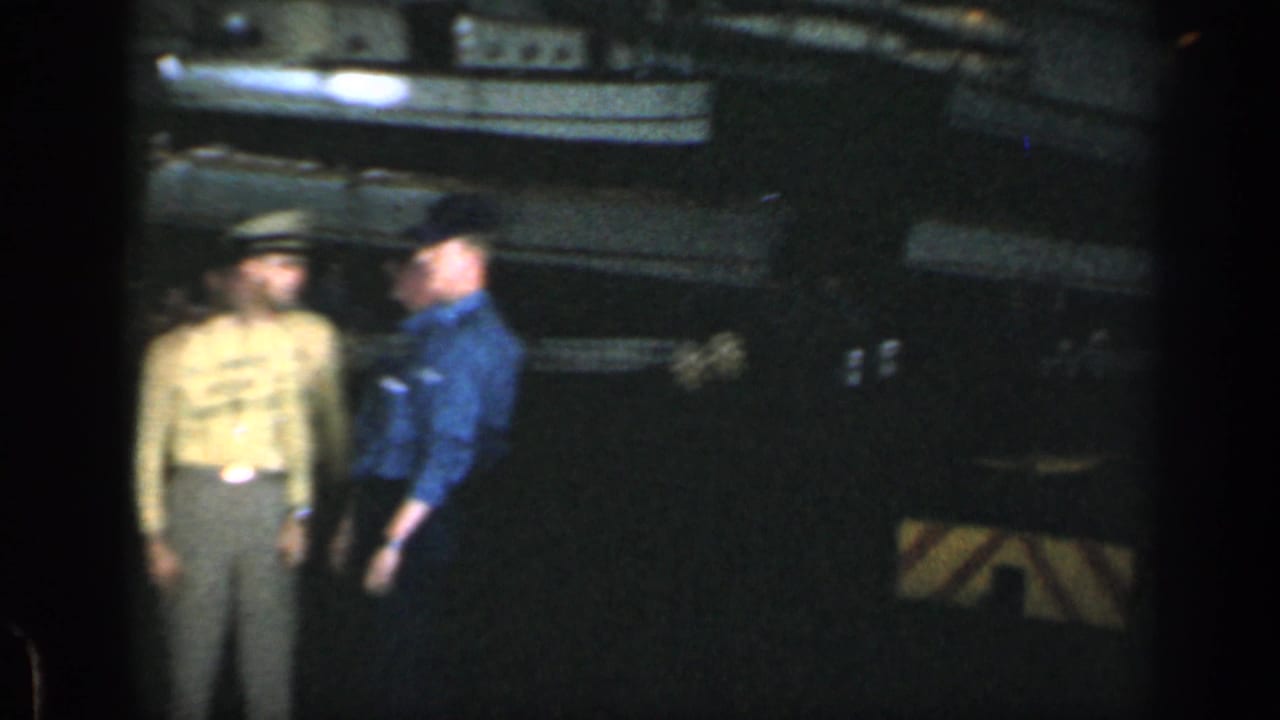 Two uniformed men appear on a dark ship deck in 1962 Cuba-associated 8mm home-movie footage.