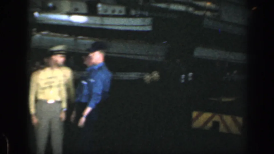 Two uniformed men appear on a dark ship deck in 1962 Cuba-associated 8mm home-movie footage.