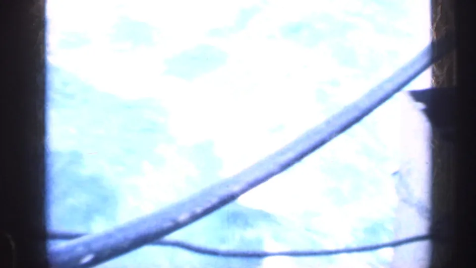A bright, overexposed view of water appears through dark framing aboard a moving vessel.