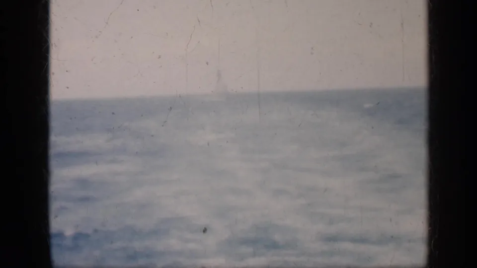 1962 Cuba 8mm frame of choppy blue-gray water and muted sky, partially blocked by a dark vertical window frame.