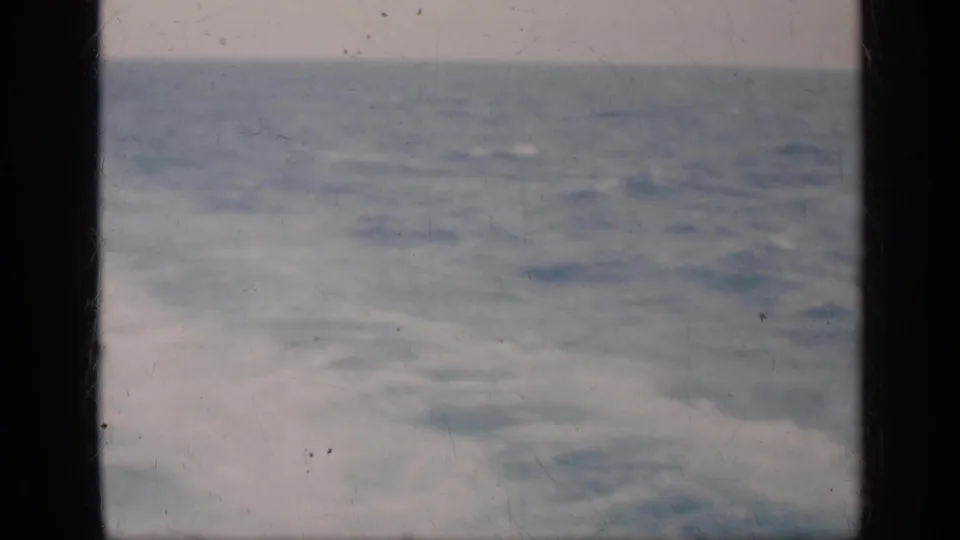 Muted 8mm view of open ocean near Cuba, with a low horizon and a dark vertical film-frame edge.