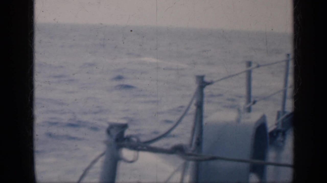 1962 Cuba 8mm frame showing open water seen past ship railings and deck fittings from aboard a vessel.