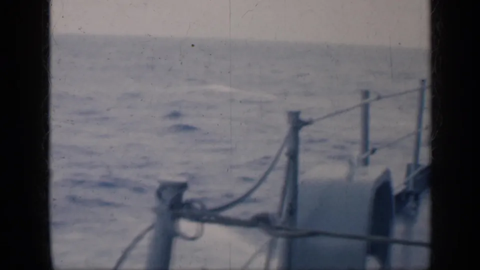 1962 Cuba 8mm frame showing open water seen past ship railings and deck fittings from aboard a vessel.