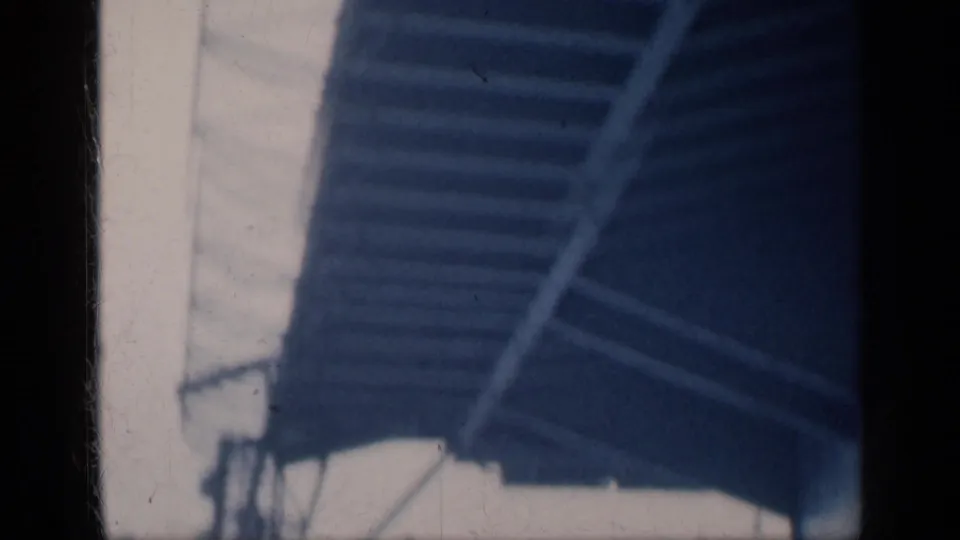 Soft 8mm frame showing an angled stairway or ladder structure on a vessel, with pale deck surfaces and dark scan borders.