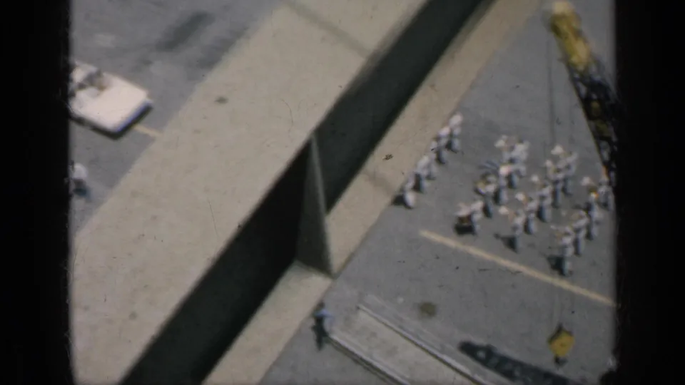 1962 Cuba 8mm view of a yellow crane near grouped uniformed figures, with a large structure crossing the foreground.