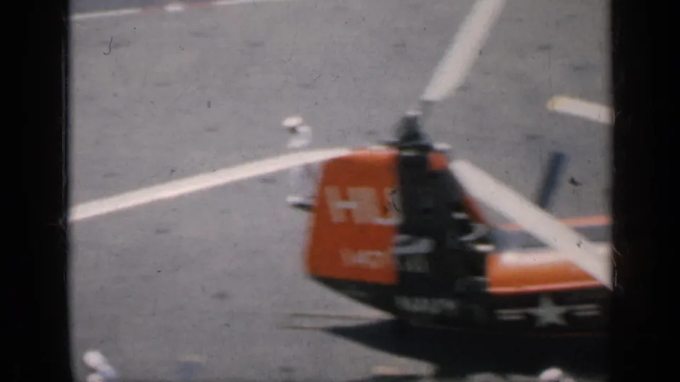 Cuba-linked 1962 8mm frame of an orange-and-black helicopter with visible markings on a carrier deck.