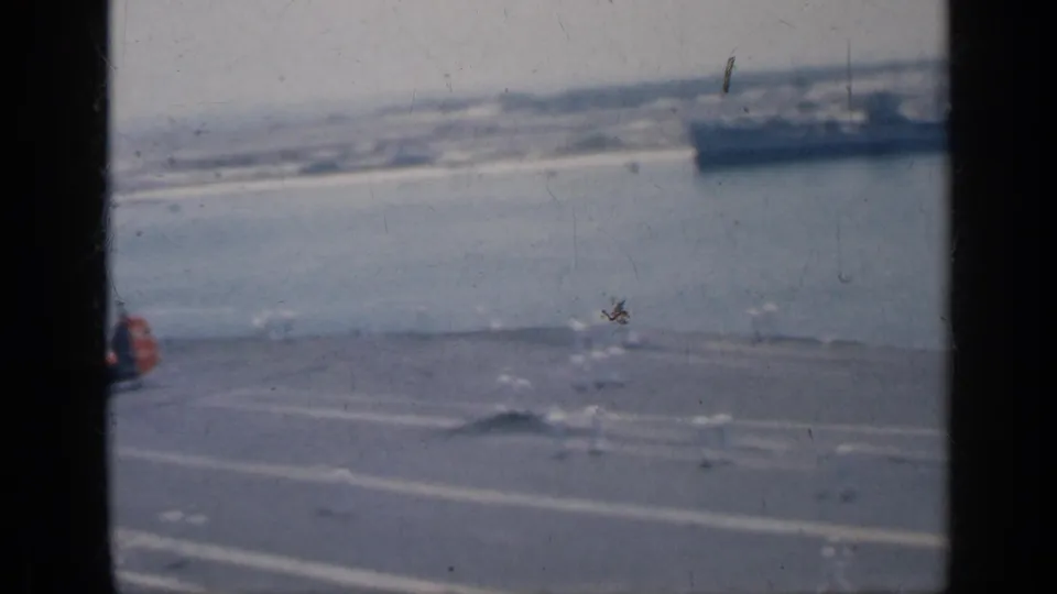 1962 Cuba frame from an 8mm naval view, with the carrier deck, a partial helicopter, open water, and a distant vessel.