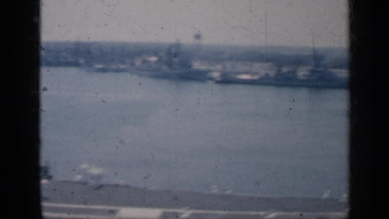 Harbor water and distant shoreline seen through dark window framing.