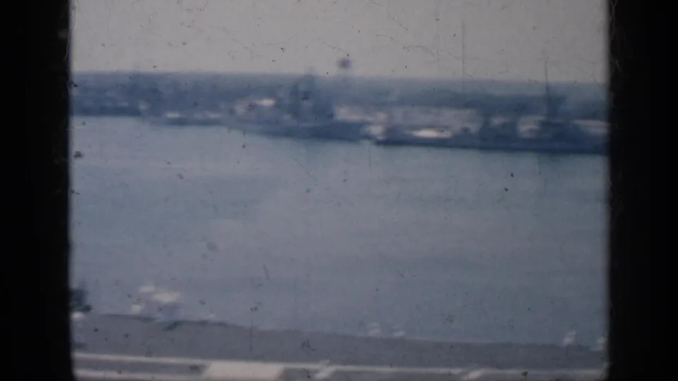 1962 Cuba harbor view through a vessel window, with water, distant shore structures, and soft 8mm texture.