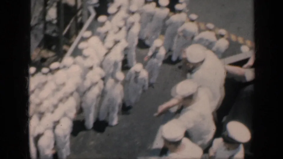 1962 Cuba home-movie frame showing sailors in white uniforms clustered and moving on a naval ship deck.
