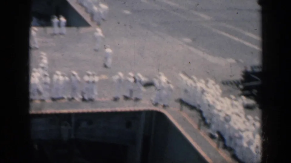 Overhead 1962 Cuba home-movie view of sailors in white uniforms lined across a naval deck with painted markings.