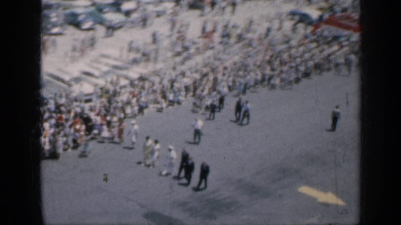 Elevated view of a large crowd beside open pavement near a beach area.