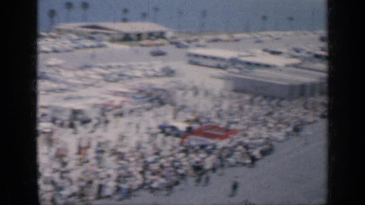 Elevated view of a crowded outdoor area with parked cars and people below.