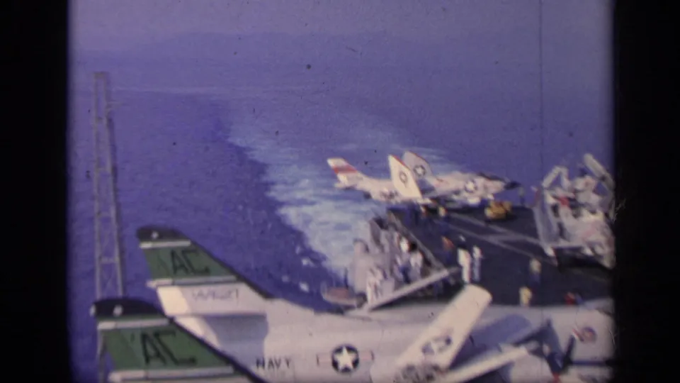 The final 1962 Italy frame shows parked U.S. Navy aircraft, sailors on deck, mastwork, and wake along the aircraft carrier at sea.