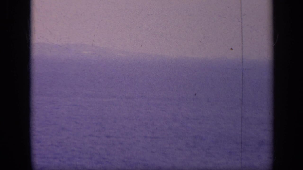 Distant warship silhouette on a hazy blue sea horizon.
