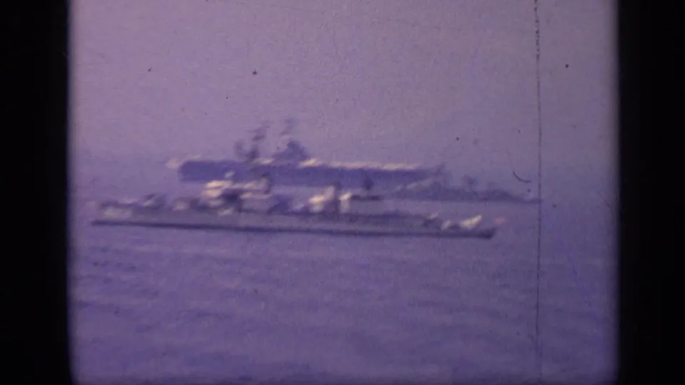 1962 Italy 8mm frame with blurred naval vessels moving across calm sea, including a larger carrier-like profile in the background.