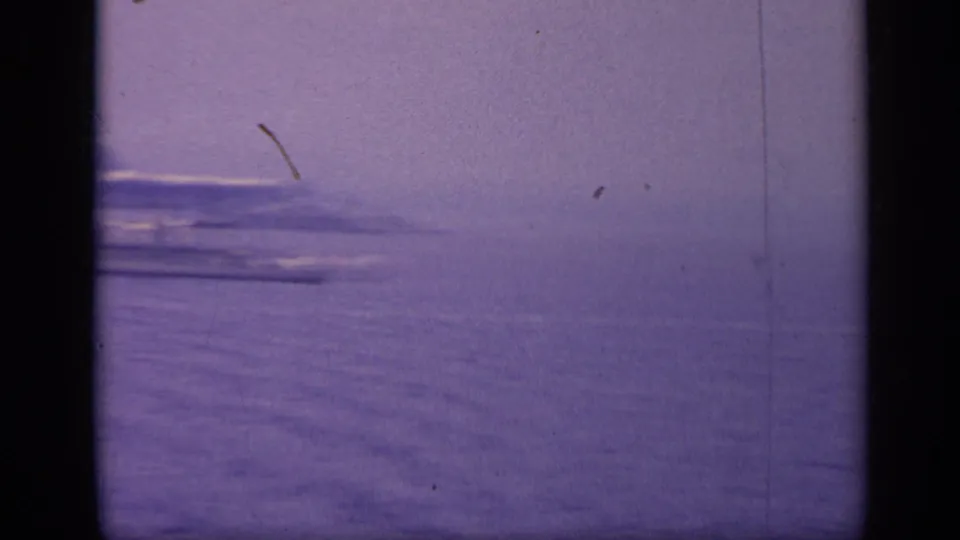 1962 Italy 8mm frame showing calm open water, a low hazy horizon, and possible distant vessels softened by grain and exposure.