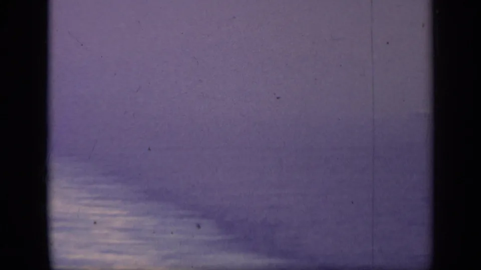 1962 Italy 8mm frame of hazy open water with a bright reflective band and minimal visible vessel detail.
