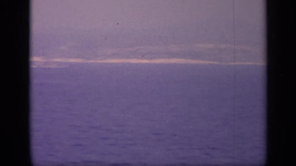 Purple-tinted 8mm frame of calm Italian coastal water, with a faint strip of land and no clear vessel visible.