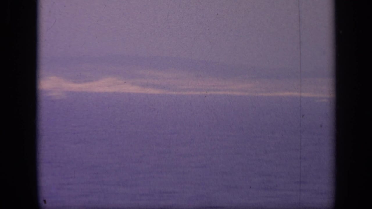 Hazy sea horizon framed by dark film edges and gate lines.
