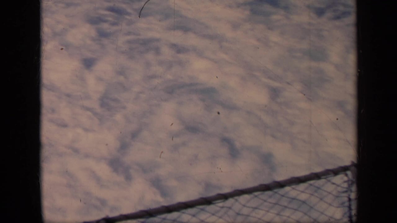 Foamy water and a diagonal chain-link railing seen from a moving boat.
