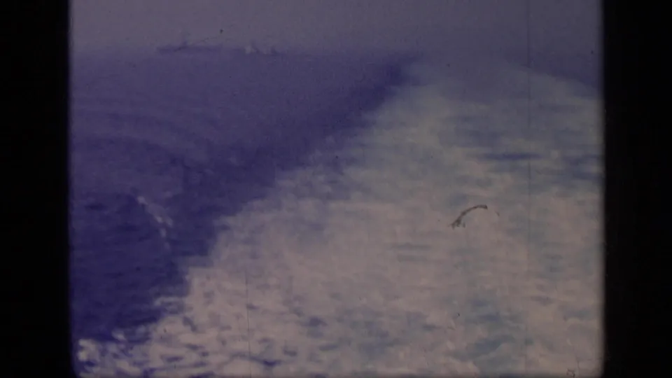 1962 Italy 8mm frame showing a blue-toned boat wake spreading across open water with visible film wear.