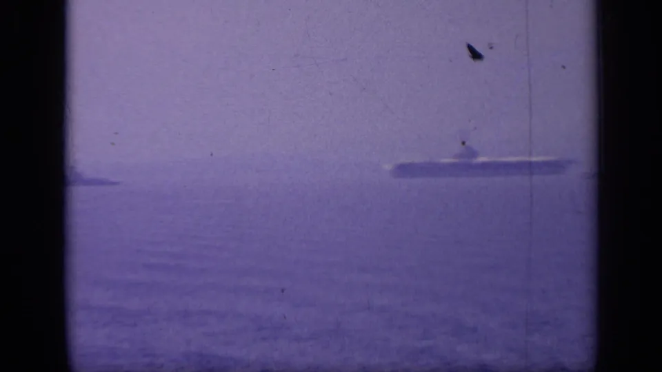 1962 Italy 8mm frame showing a distant ship profile on the horizon with muted blue-purple film color.