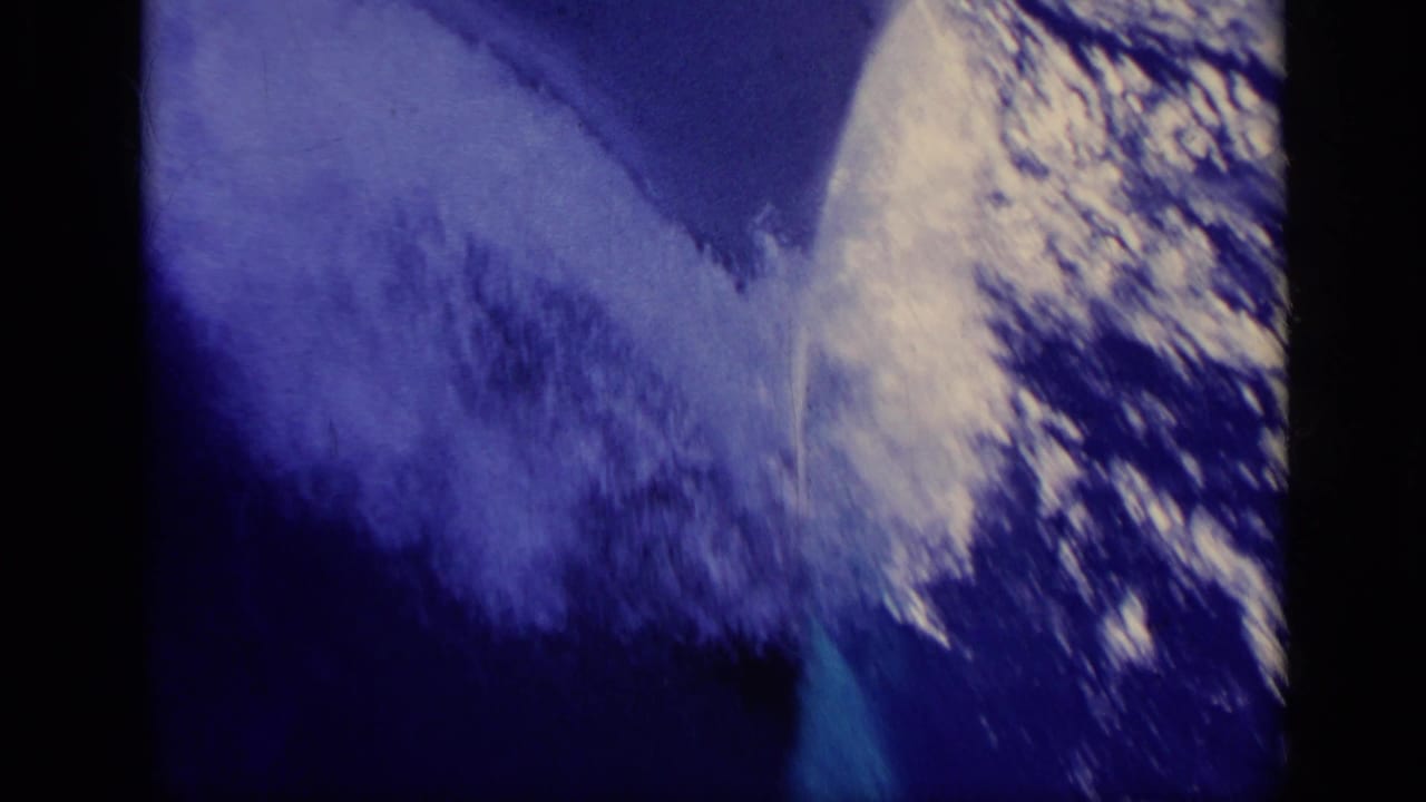 Blue-tinted 8mm view of a fast-moving boat beside foaming water, with dark gate edges and film wear visible.