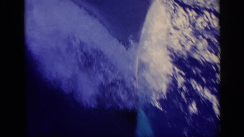 Blue-tinted 8mm view of a fast-moving boat beside foaming water, with dark gate edges and film wear visible.