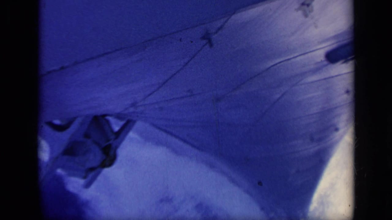 1962 Italy home-movie frame showing a close, tilted view of boat material with a partial dark onboard shape and film scratches.