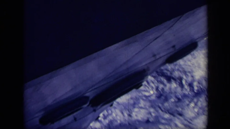 1962 Italy 8mm frame showing a large ship's side and bow area moving through foamy water from a divided passenger viewpoint.