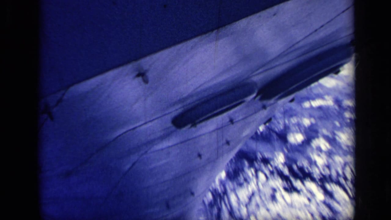 Large ship hull angled across the frame above white-capped ocean water.