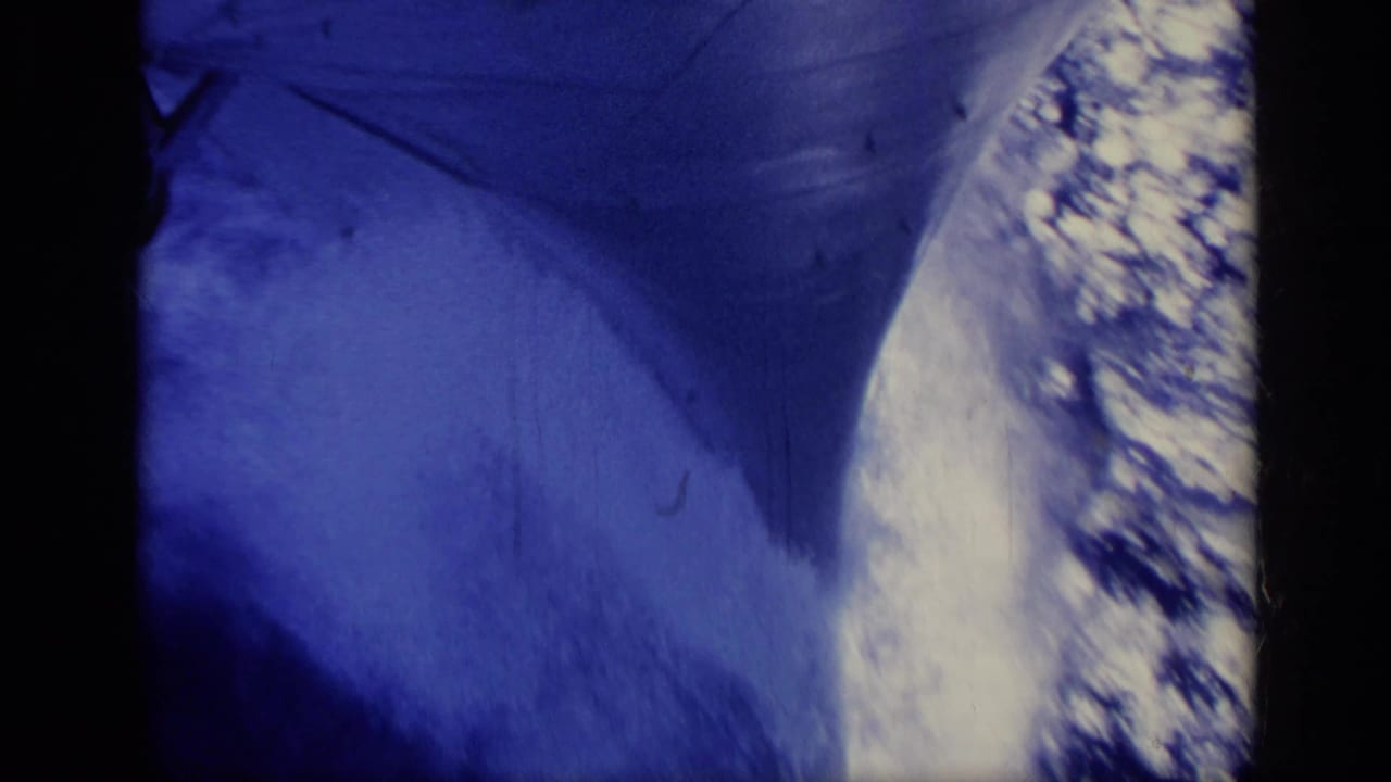 Dark ship bow or hull edge over blue water with bright foam along the side.
