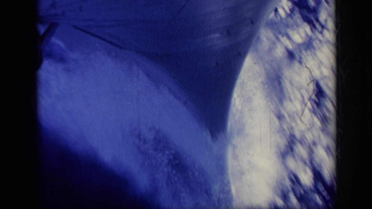 Blue-toned close view of sea wake beside a large ship.