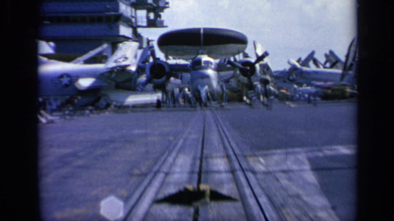 Closer carrier deck view of a radar-equipped propeller aircraft with other planes nearby.