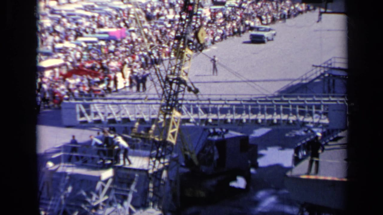 Crowded pier beside a large ship with rigging and deck equipment in view.