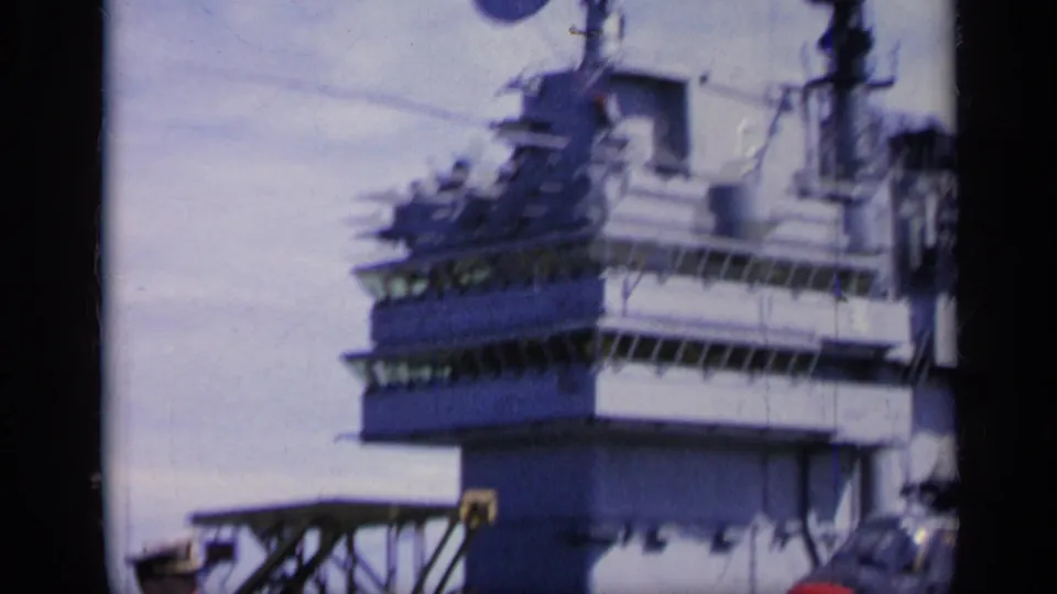 1962 Italy home-movie view of the carrier island structure, with platforms, railings, and deck equipment visible.