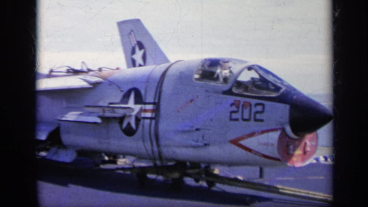 U.S. Navy jet marked 202 on an aircraft carrier deck with star insignia visible.