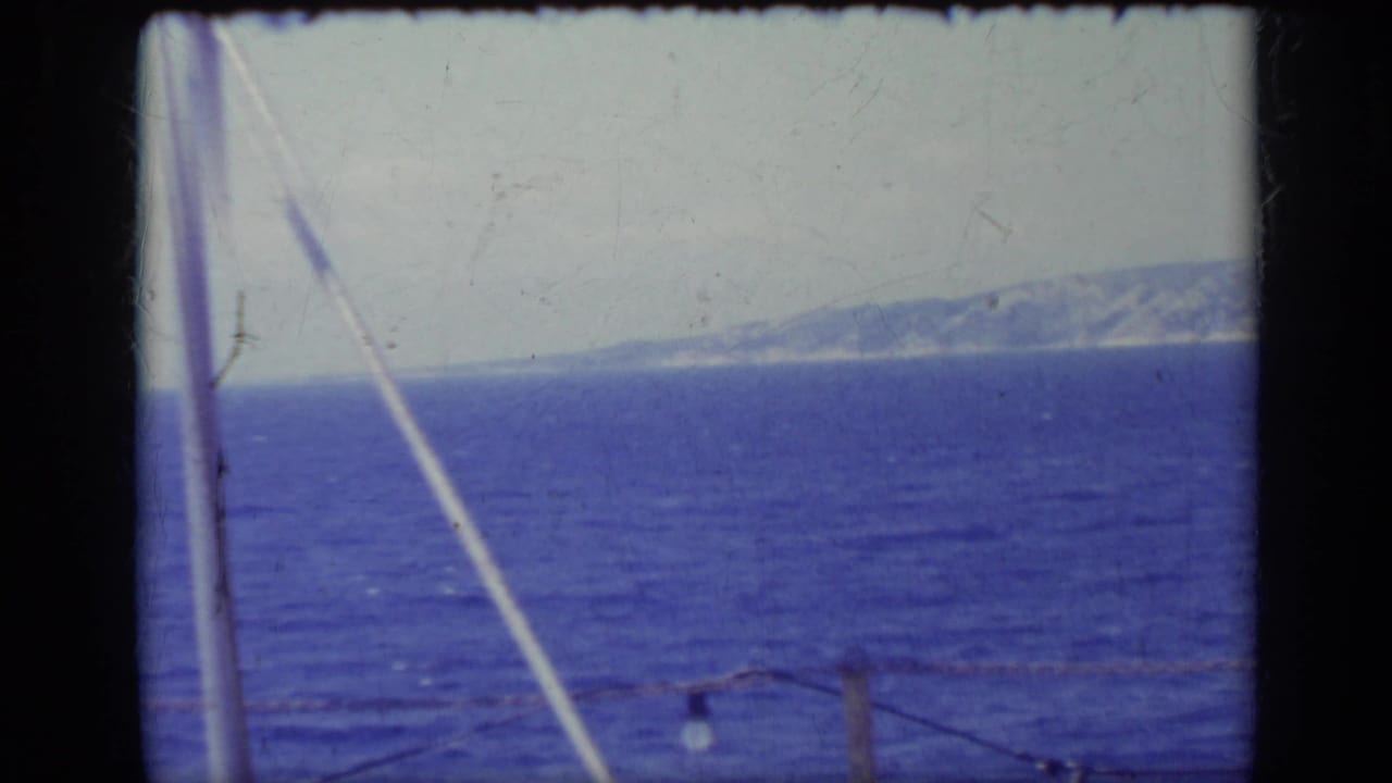 Dark blue water and distant mountain coastline seen past a rope with small bulbs.